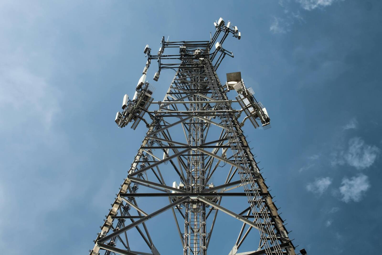 Cell tower rising into a blue sky